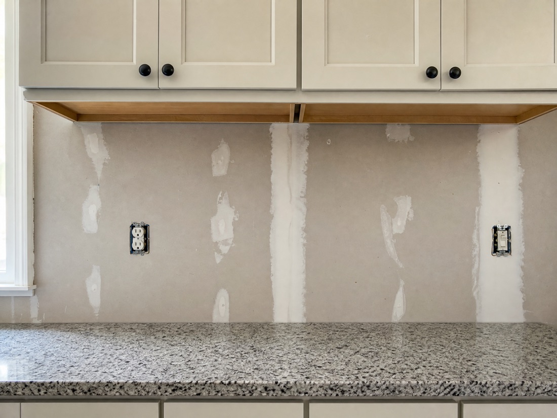 Before: plain kitchen wall with bare drywall and no backsplash